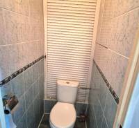 Small bathroom with a toilet and tiles in a 2-room apartment, roller blind on the window.