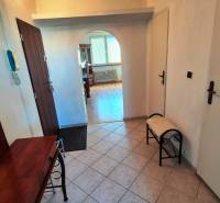 A hallway with an arched passage in a 2-room apartment, a floor with a wooden decor, a mirror, a bench.