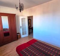 Bedroom in a 2-room apartment with a wooden decor floor, wardrobe, and bed.