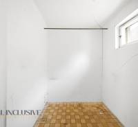 Empty room with a window, white walls, and tiled floor with cracks in a family house.