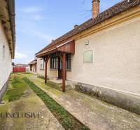 A family house in Topoľníky with a well-maintained facade, a veranda, and a concrete walkway.