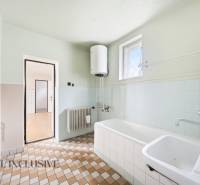 A bathroom in a family house with a shower, sink, radiator, and heating boiler.