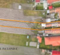 A family house in Topoľníky with a garden in the frame, visible agricultural field and buildings.