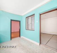 A room in a family house with colorful walls, laminate flooring, and a large window.