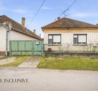 A family house in Topoľníky with a green gate and metal fence, sloped roof.