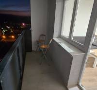 A balcony of a studio apartment in Pod Hájom, Dubnica nad Váhom, with a folding chair and a tiled floor.