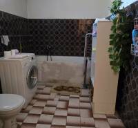 A bathroom in a family house with a washing machine and decorative wall tiles.