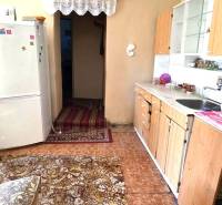 A kitchen in a family house with wooden decor, a refrigerator, and a carpet.