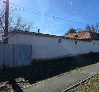 Pavlovce nad Uhom, a family house with a metal roof and fencing, next to a narrower road.