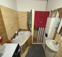 Bathroom in a 3-room apartment with a bathtub, sink, and washing machine; storage space.