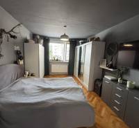 A bedroom in a 3-room apartment with a wardrobe, bed, and wooden decor flooring.
