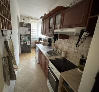 A narrow kitchen with a kitchen unit and a wooden decor floor in a 3-room apartment.