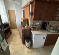A kitchen with a wooden floor decor in a 3-room apartment with wooden cabinets and appliances.