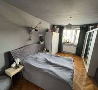 Bedroom in a 3-room apartment with a bed, wardrobe, and wooden decor flooring.