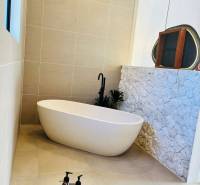 A bathroom in a family house with a freestanding bathtub and stone wall cladding.