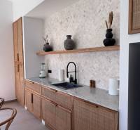 A kitchen with a natural/organic design, a sink, an open shelf with ceramic decorative items.