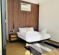 Bedroom in a family house with a patterned wall, fan, carpet, and wood-patterned flooring.