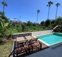 Sunbeds and loungers with a view of greenery on Amed Street, Amed, next to a family house.