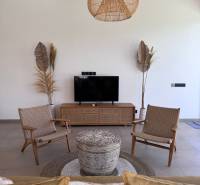Living room of a family house with wooden decor, television, and wicker furniture.
