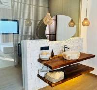 Bathroom in a family house with a sink on a wooden shelf and a floor with a wood decor.