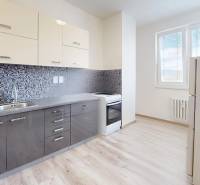 Kitchen in a 2-room apartment with a modern kitchen unit and flooring with a wood decor.