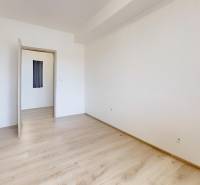 A room with white walls and a wooden decor floor in a 2-room apartment.