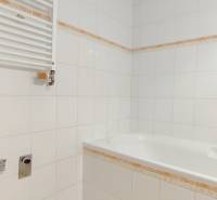 Bathroom with a bathtub and white tiles in a 2-room apartment.