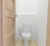 Bathroom with beige tiles in a 2-room apartment, toilet and white walls.