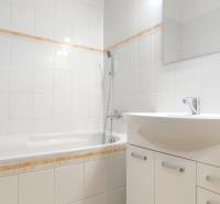 Bathroom in a 2-room apartment with white tiles and a bathtub.