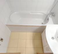 Bathroom in a 2-room apartment with a bathtub, sink, and white tiles.