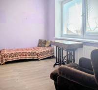 A room in a family house with a sofa bed and an armchair, flooring with a wooden decor.