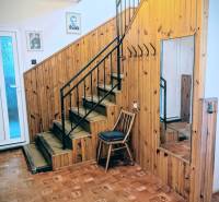 Interior of a family house with wooden paneling, a mirror, a staircase, and a floor with a wooden decor.