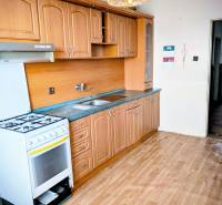 A kitchen in a family house with a classic kitchen unit and a floor with a wooden decor.