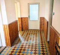 A hallway in a family house with a tiled floor and wooden paneling on the walls.