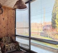 Family house with a rattan lamp, an armchair with a blanket, and windows with blinds.