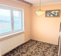 In the family house, there is a room with a carpeted floor, a hanging chandelier, and a painting.