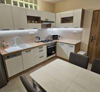 A kitchen in a 2-room apartment with wooden decor, modern equipment, and a dining table.