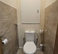 A toilet with tiles and a ceramic toilet in a 2-room apartment.
