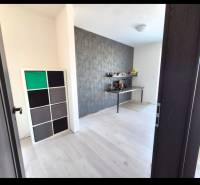 A room in a 3-room apartment with a wooden decor floor and a decorative wall.