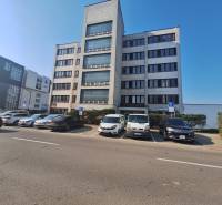 Office building on Tulská Street in the city of Zvolen, with a parking lot and parked cars.