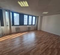 A spacious office with large windows and a wooden decor floor.