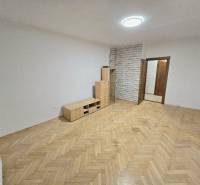 A bright room in a two-room apartment with a wood-decorated floor and furniture.