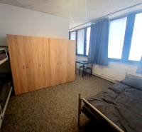 Furniture in the interior of a building with beds, a wardrobe, and a table on a carpet.