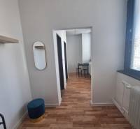 Interior of a building with wood-patterned flooring, chairs, mirror, white ceiling.