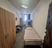 The interior of a building with two beds, wardrobes, and a small table in the room.