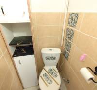 Toilet in a one-room apartment with stone decor on the tiles and toilet.