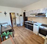 A kitchen in a studio apartment with a wood-patterned floor, nicely furnished and functional.