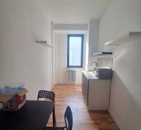 A narrow office with a black desk, chairs, and a wooden decor floor.