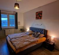 A bedroom with a double bed, a desk, and a wooden decor floor in a 3-room apartment.