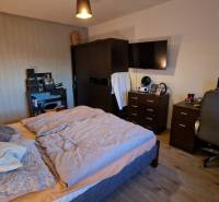 Bedroom in a 3-room apartment with a comfortable bed, a work desk, and a floor with a wooden decor.